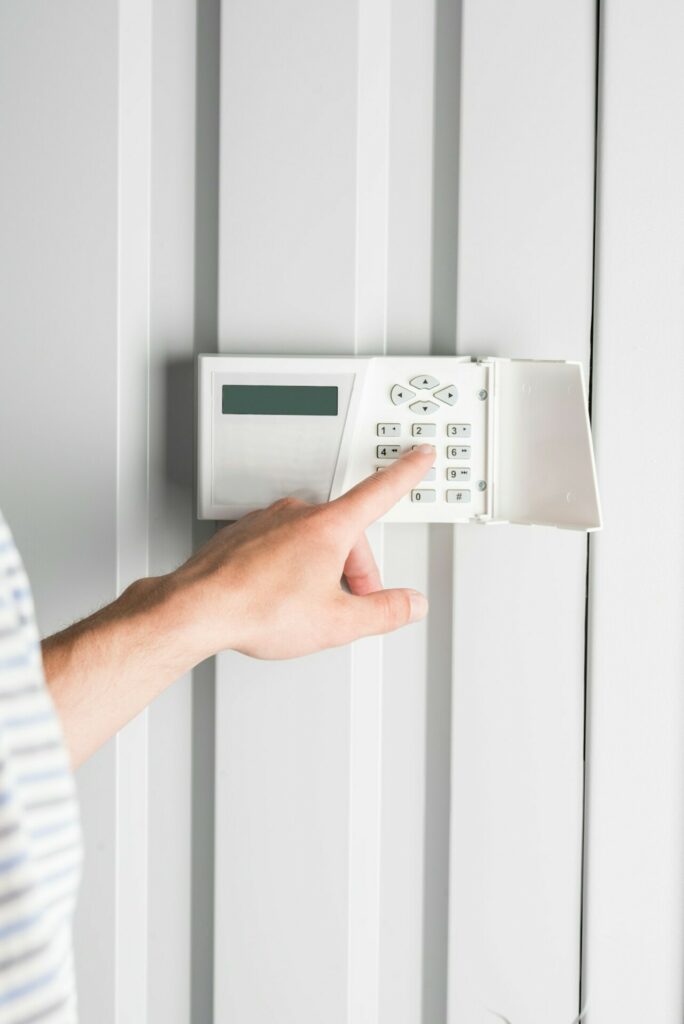 person typing password on home security alarm, security system concept